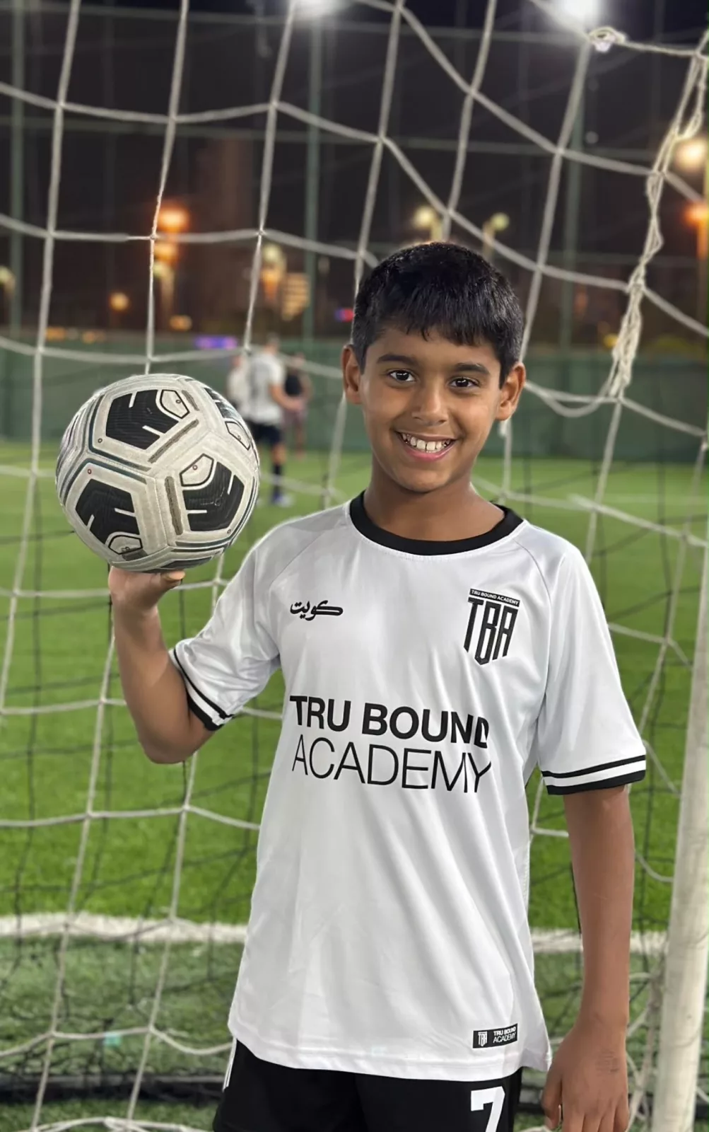 Young academy player holding a football beside the goal