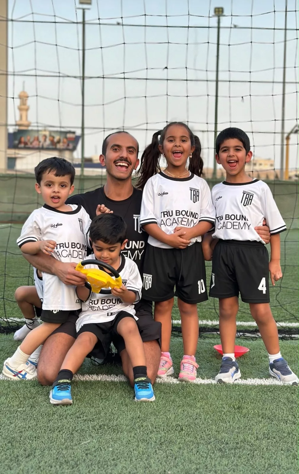 Coach with young academy players on the football pitch
