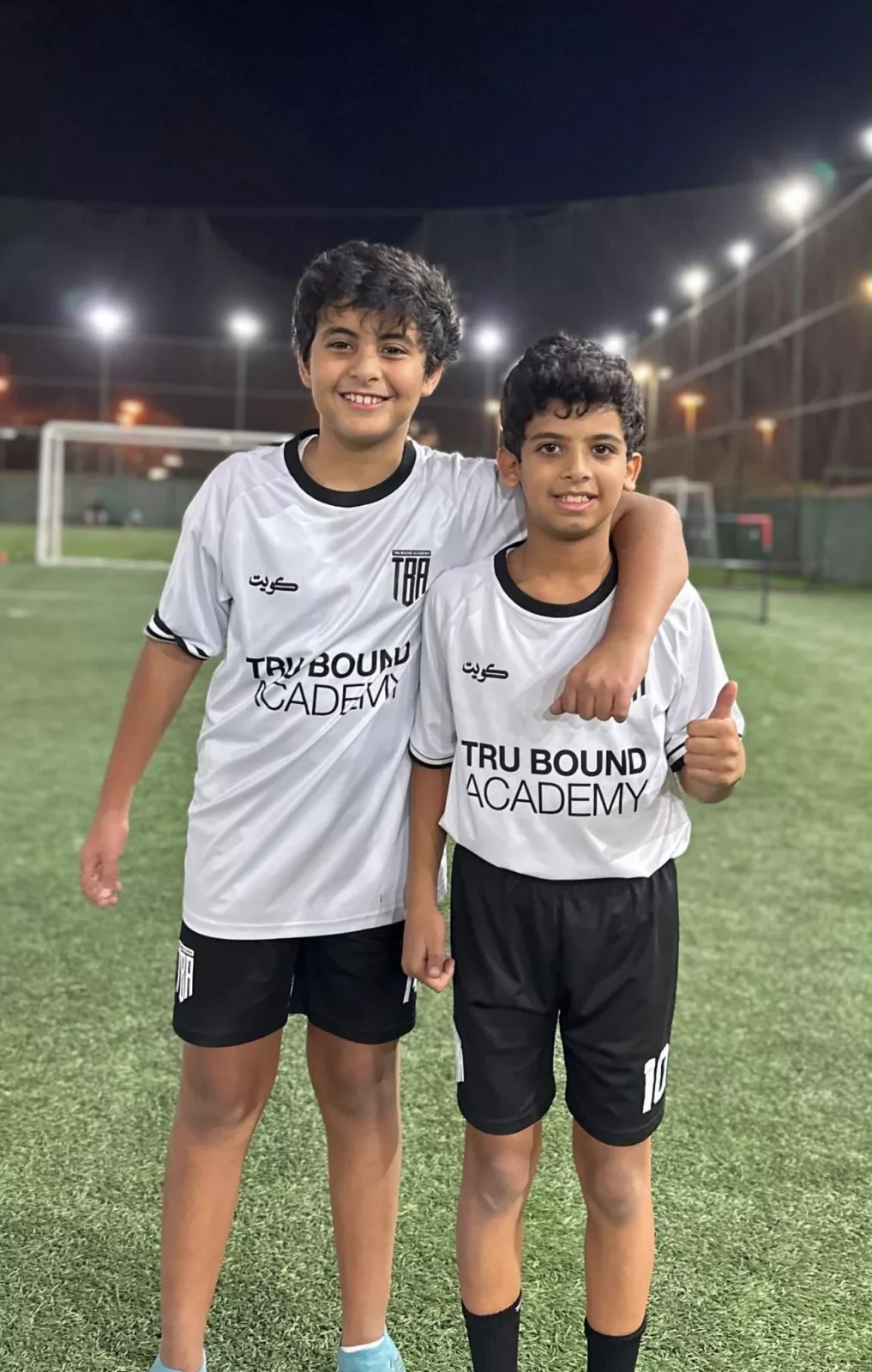Two academy players standing together under the floodlights