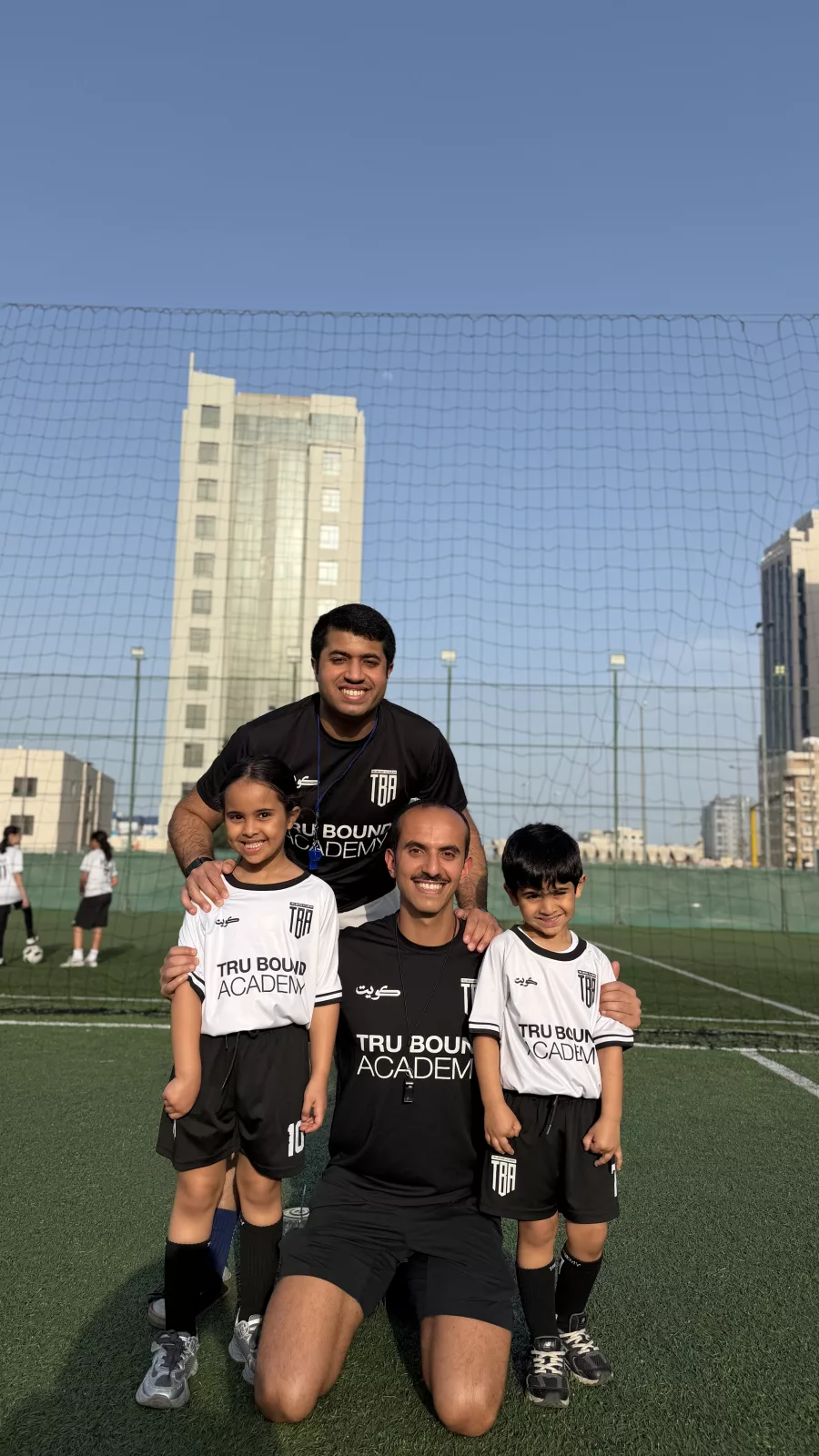 Coaches and young players posing on the football pitch