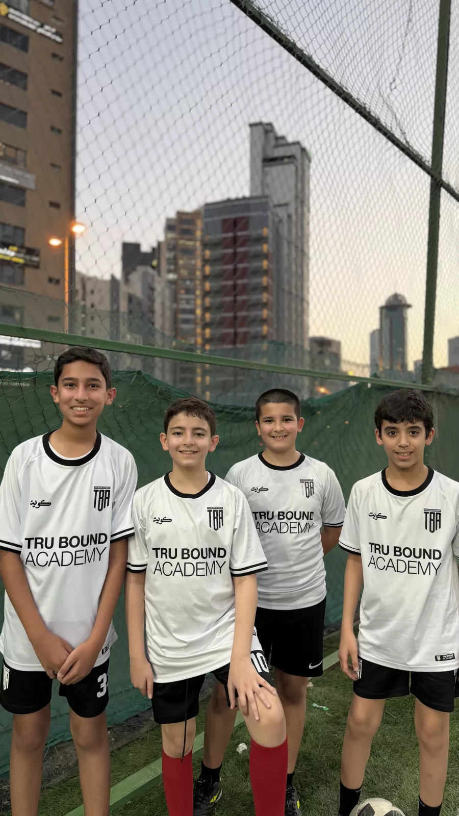 Four academy players standing beside the pitch